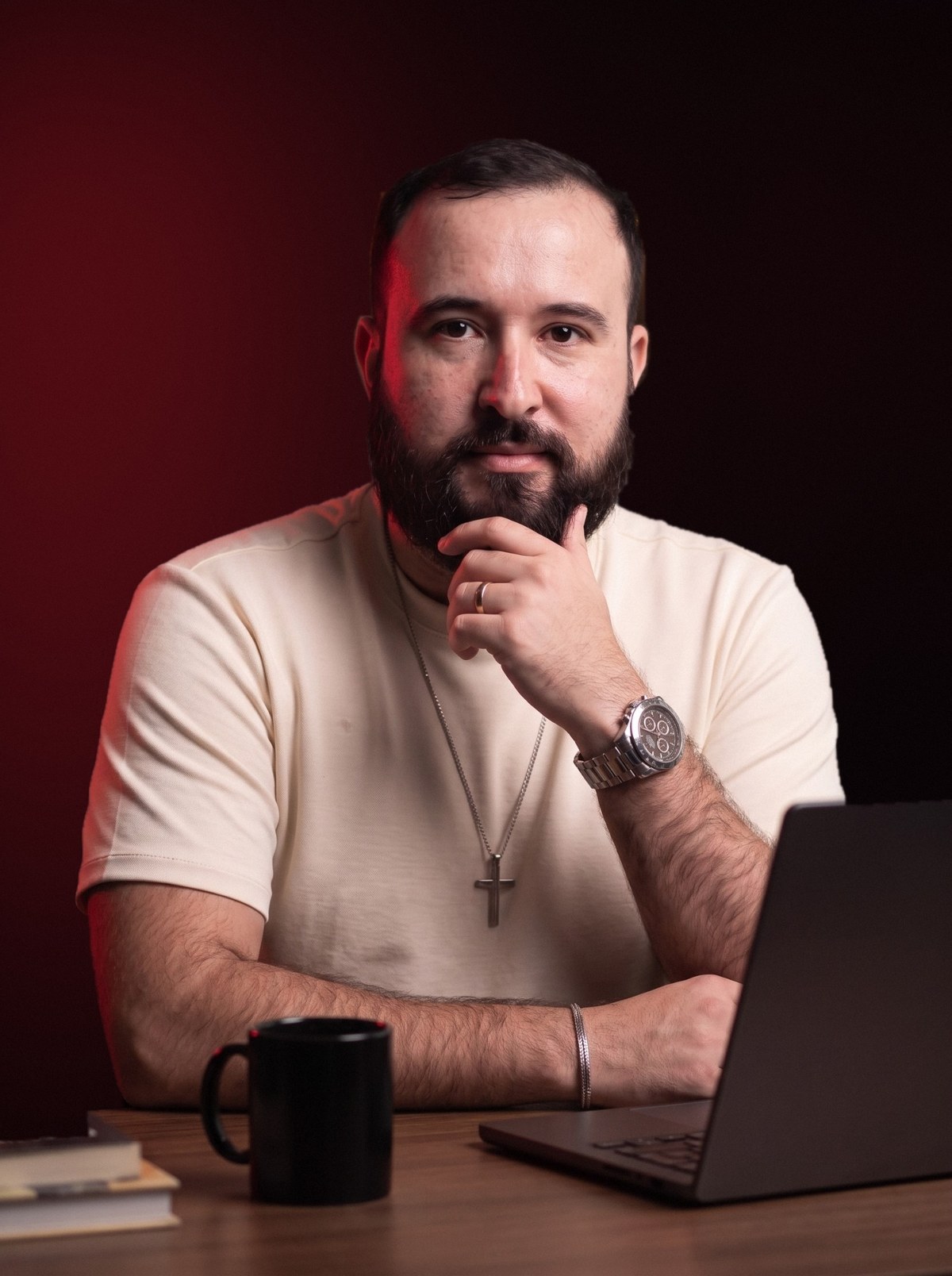 Junior Rodrigues sentado em seu escritório, com o notebook à frente e a mão no queixo